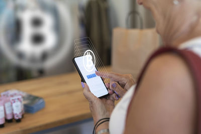 Woman paying with bitcoin crypto currency in store