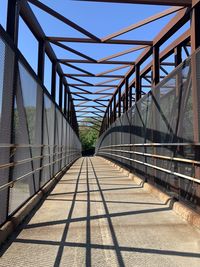 Footbridge over footpath against sky