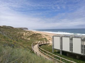 Boardwalk by shelter at beach against sky