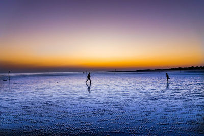 Silhouette person on sea against clear sky during sunset