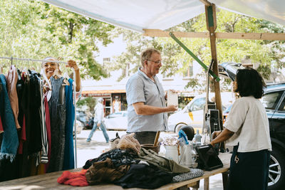 Senior male customer communicating with owner near stall at flea market