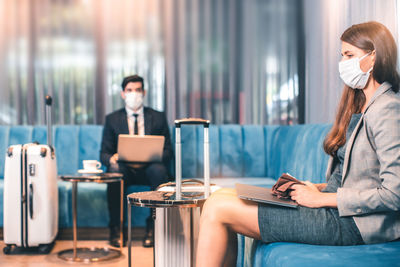 Young woman using mobile phone while sitting on table