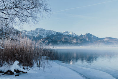 Scenic view of frozen lake by snowcapped mountains against sky