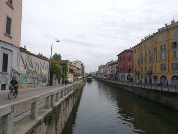 Canal amidst buildings in city against sky