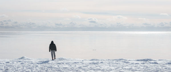 Rear view of man on sea shore against sky