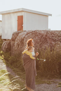 Mother with baby girl looking away while standing by rock formation