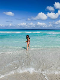 Woman standing in sea against sky