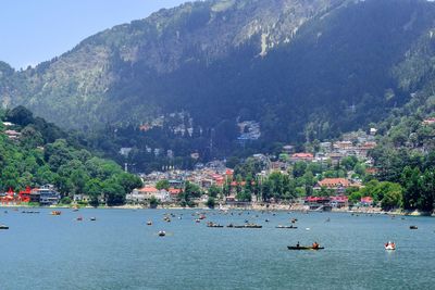 Sailboats in sea by city against mountain