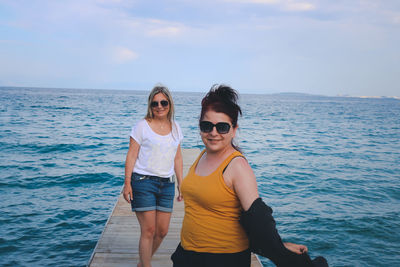 Portrait of friends in sea against sky