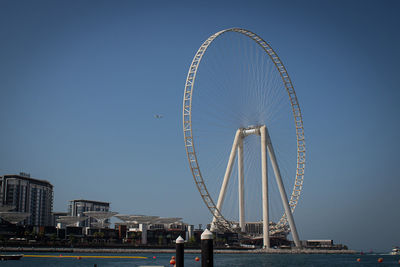 Ferris wheel in city against clear blue sky