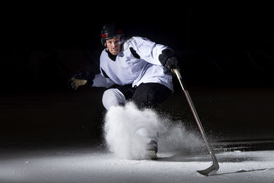 Portrait of man playing ice hokey at night