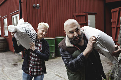 Smiling coworkers carrying sacks while walking towards brewery