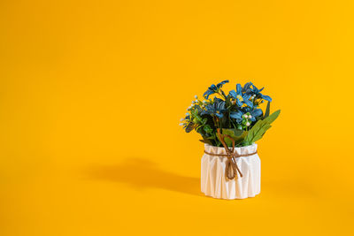 Close-up of flower vase against orange background
