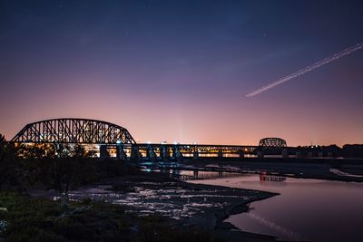 Silhouette bridge against sky at night