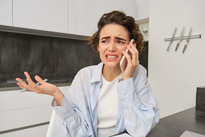 Young woman using mobile phone while sitting on table