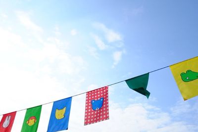 Low angle view of flags hanging against blue sky