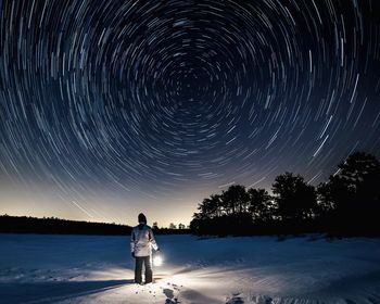 Man standing on snow field against sky at night