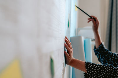 Midsection of woman reading book against wall