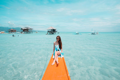 Young woman on beach against sky