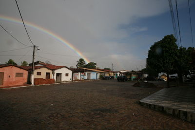 Rainbow over town against cloudy sky