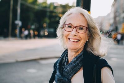 Portrait of happy wrinkled woman wearing scarf in city