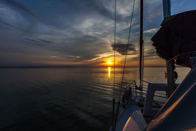 Low section of man sailing on sea against sky during sunset