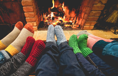 Low section of people wearing socks against fireplace