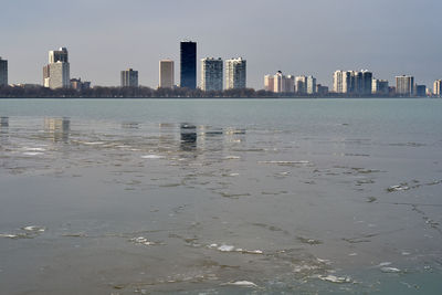 Sea by buildings against sky in city