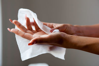 Close-up of woman holding hands over white background
