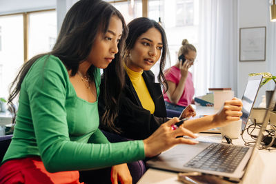 Focused businesswomen discussing over laptop at desk in office