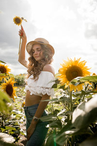 Portrait of young woman standing amidst sunflowers