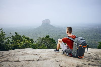 Backpack man looking at mountains from cliff 