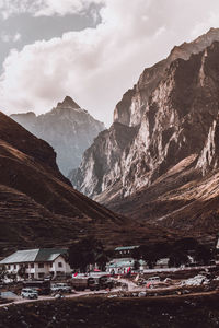 Houses by mountains against cloudy sky