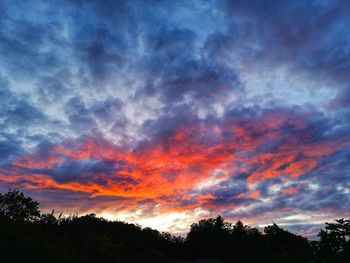 Low angle view of silhouette trees against dramatic sky