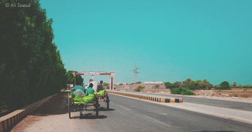 People sitting on road against clear sky