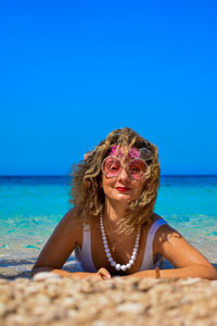 Portrait of woman at beach against blue sky