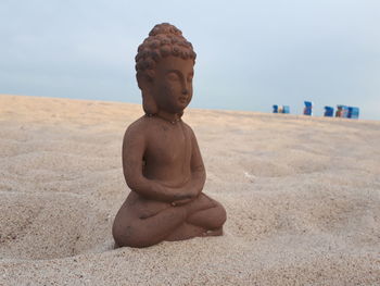 Close-up of statue on beach against sky
