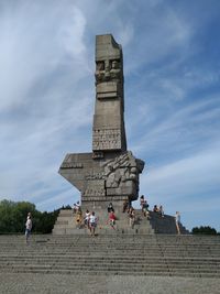 Group of people walking in front of historical building against sky