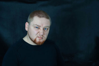 Close-up portrait of angry man against black backdrop