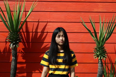 Portrait of young woman against wooden wall