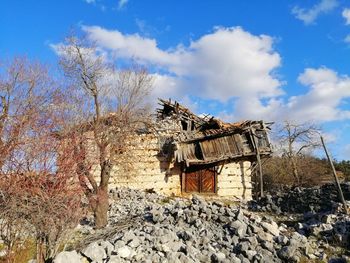 Abandoned house by tree against sky