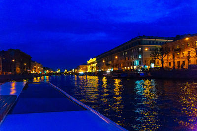 Illuminated buildings against blue sky at night