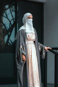 Portrait of veiled woman with white niqab and hijab walking down the stairs