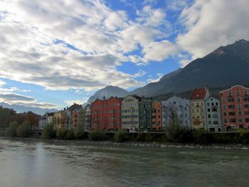 Buildings by river against sky in city