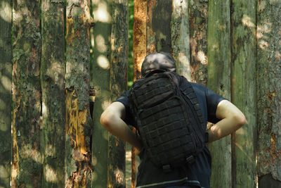 Rear view of man standing by tree in forest