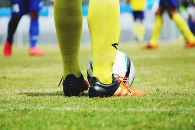 Low section of sportsperson playing soccer on grass