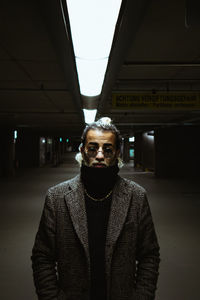 Portrait of man standing against illuminated ceiling