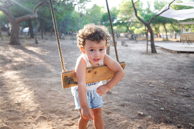 Portrait of cute girl playing with swing in playground