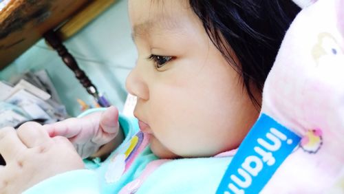 Close-up of cute baby girl looking away while lying on bed at home