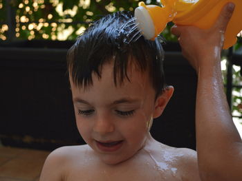 Cropped girl pouring water on brother head with toy